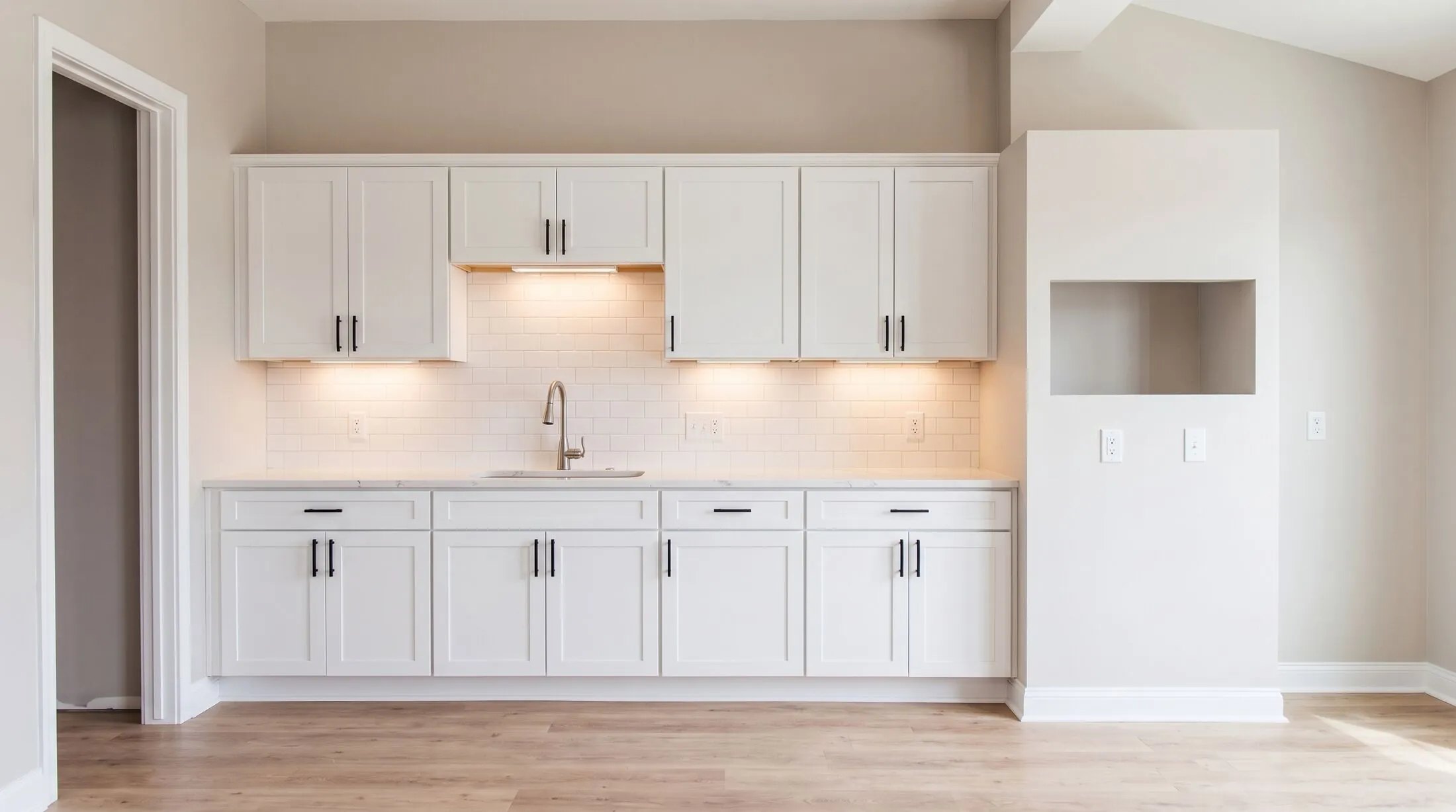 The kitchen finished: white shaker cabinets, quartz counters, subway tile and the under-cabinet lights on