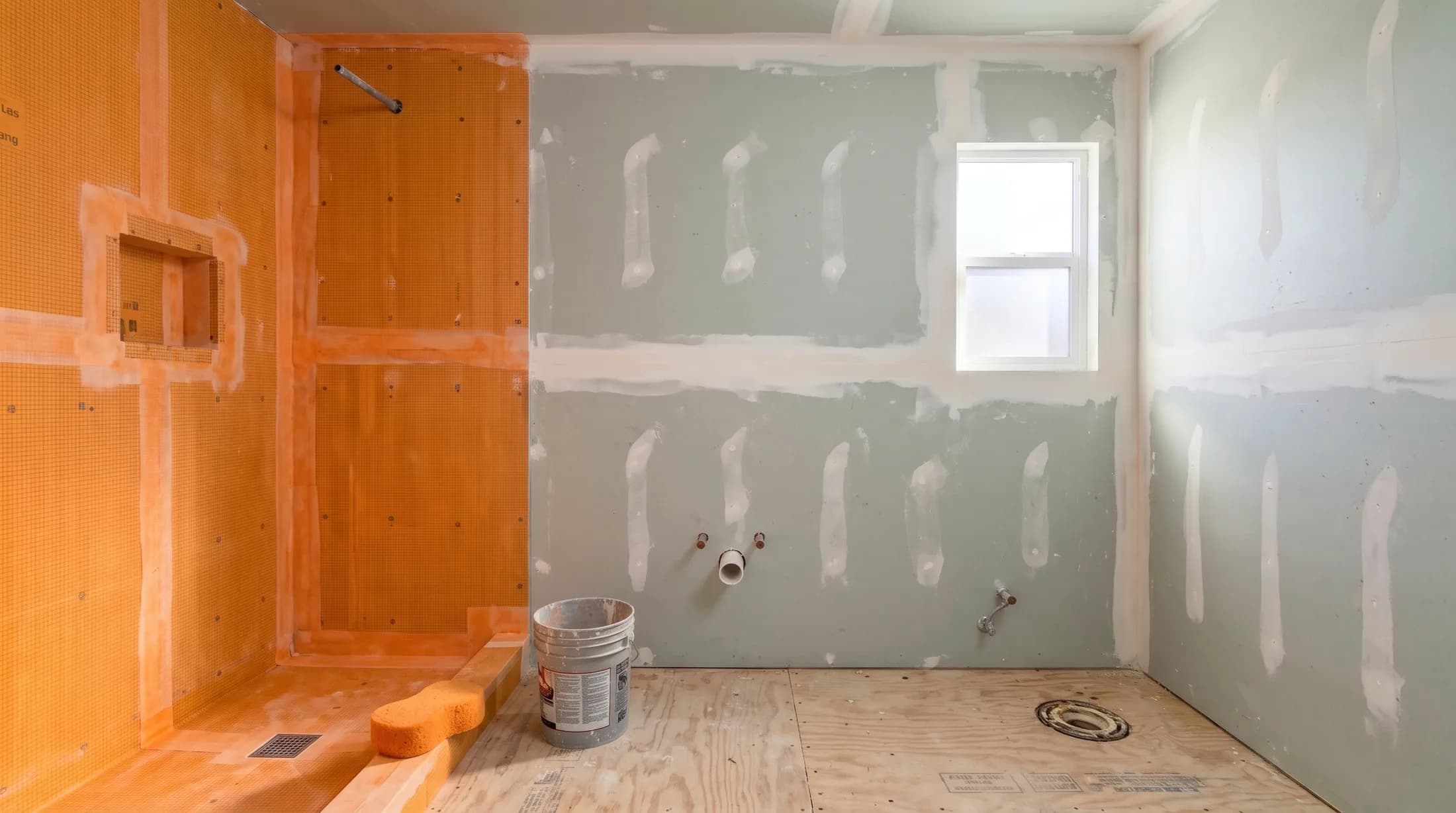 The same room with cement board up and the shower walls and floor sealed in an orange waterproofing membrane